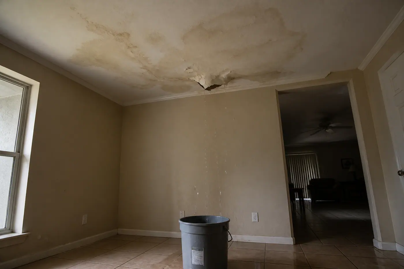 Water-stained, sagging ceiling in a Florida home with a bucket catching drips.